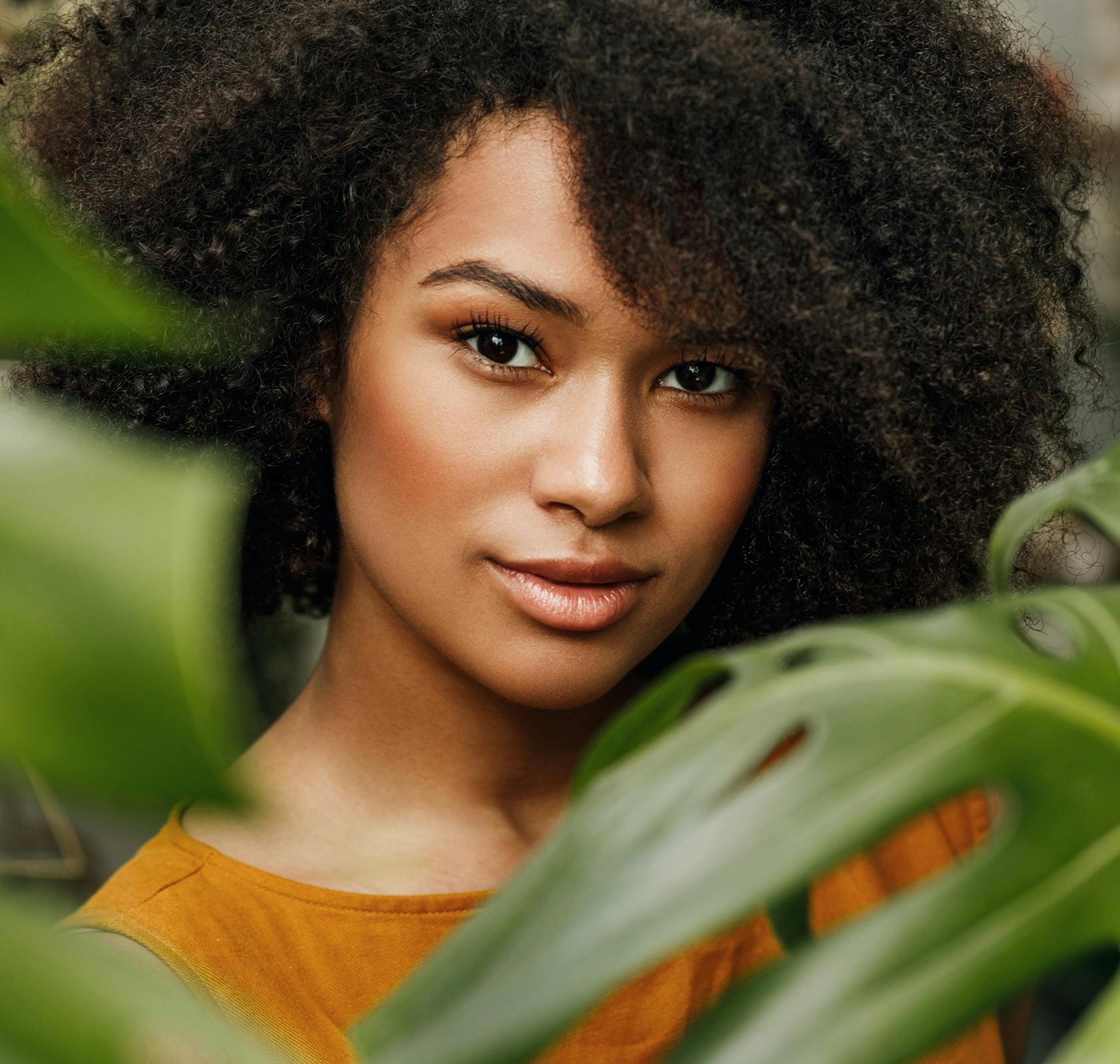 there is a woman with a large afro standing in front of a plant
