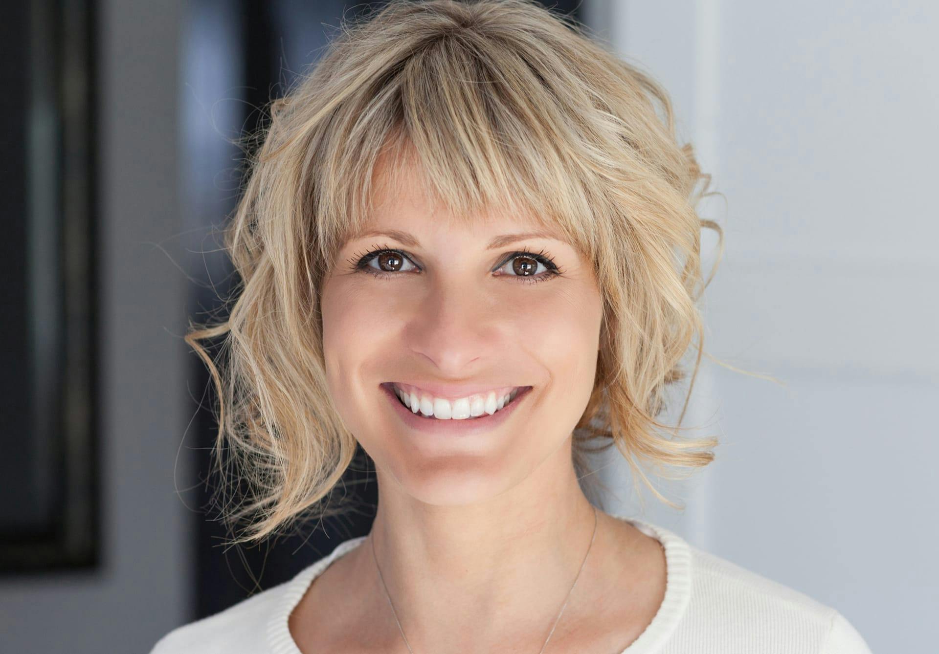 Woman with short curly blonde hair smiling