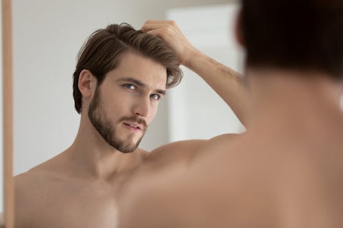 Man touching his hair while looking in the mirror