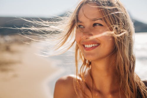 Woman with blonde hair smiling at the beach
