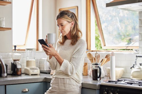 Woman in her kitchen looking at phone