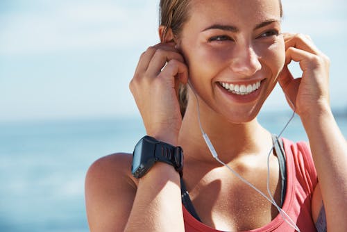 woman smiling outside wearing headphones