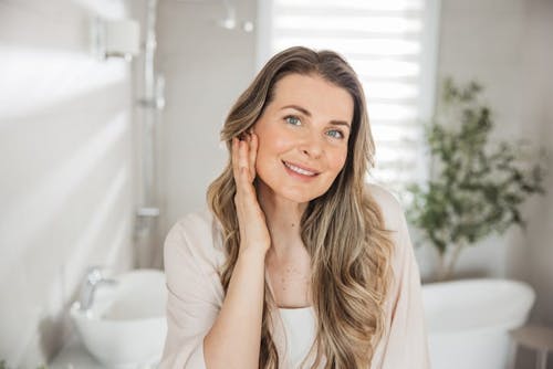 Woman admiring her skin in bathroom mirror