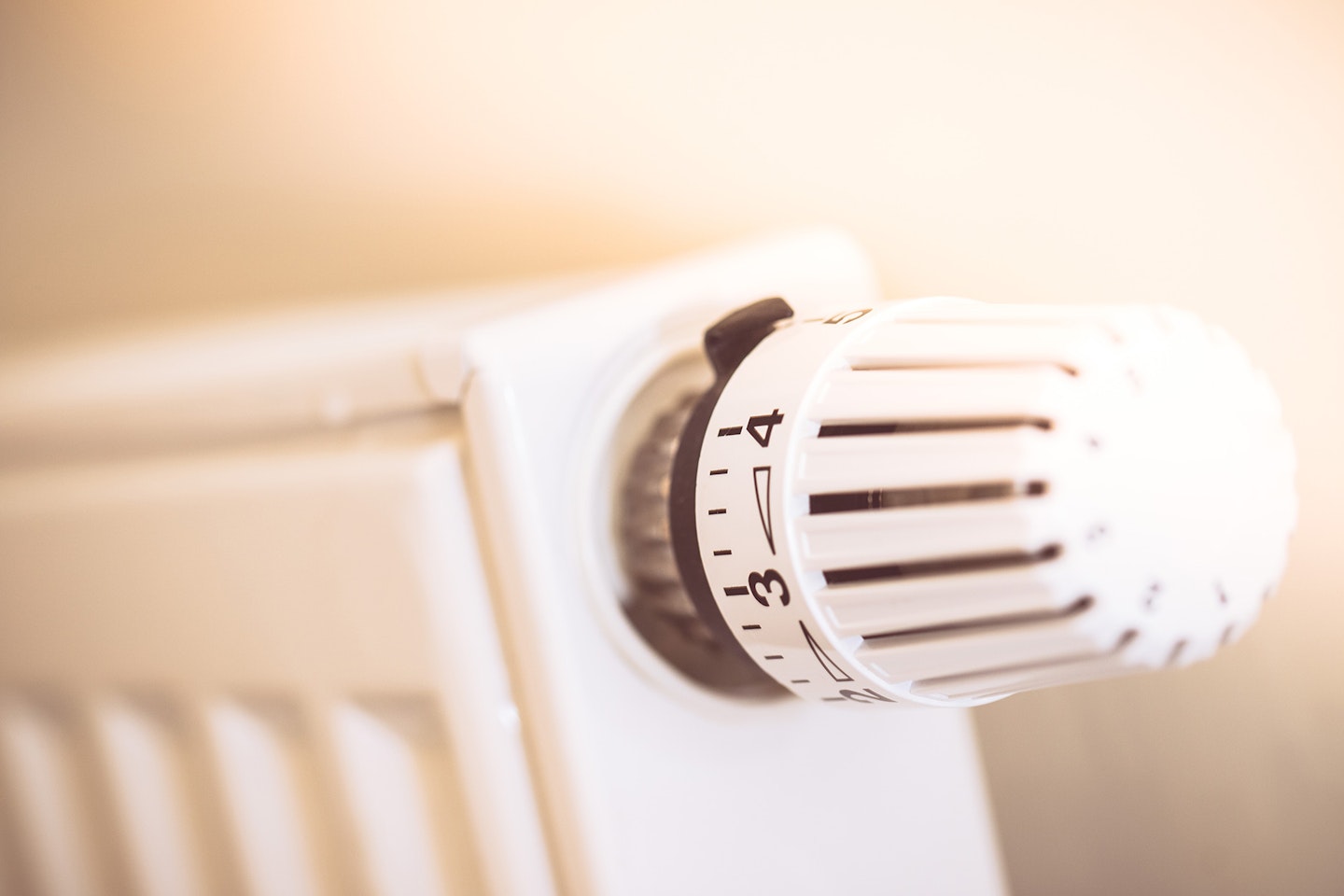 Ein weißer Heizkörper mit einem Thermostatventil, das auf die Einstellung 3 gedreht ist, strahlt Wärme in einem sanften Licht aus.