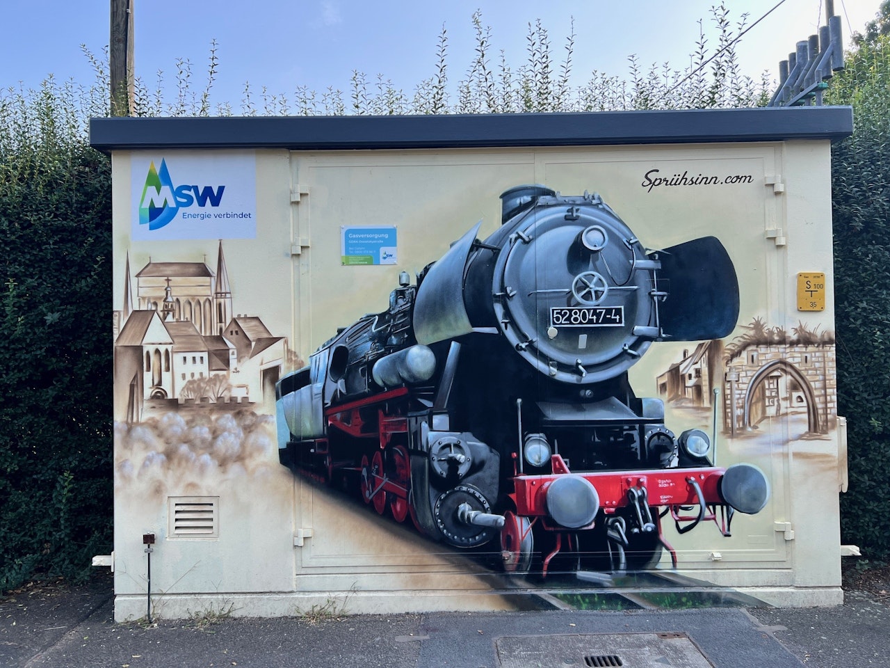 Ein realistisches Graffiti eines alten Dampflokzugs, flankiert von historische Architekturmotiven, ziert die Wand eines Versorgungskastens mit dem Logo der MSW Energieversorgung.