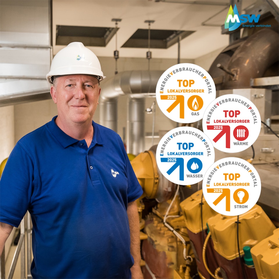 Eine Person in blauer Kleidung steht in einem industriellen Raum mit einem weißen Schutzhelm vor einer Maschine, links durch eine Metallbarriere geschützt, während mehrere Auszeichnungen zur Anerkennung der Energieversorgungskompetenz daneben sichtbar sind.