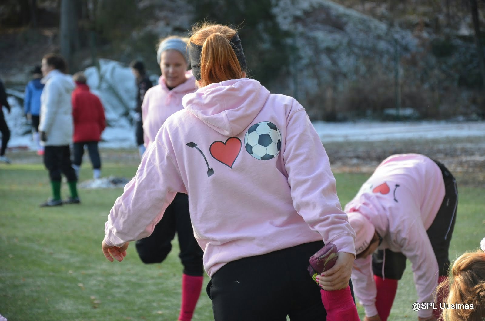 Naiset alkuverryttelevät vaaleanpunaiset "i love football" -hupparit päällä.