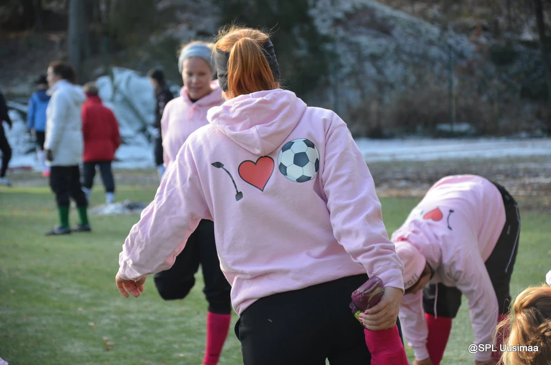 Naiset alkuverryttelevät vaaleanpunaiset "i love football" -hupparit päällä.
