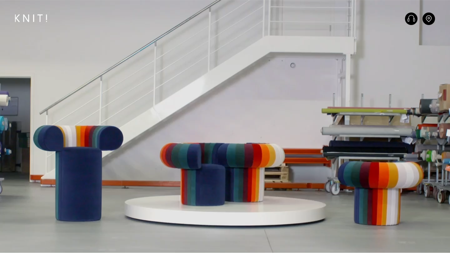 Three modern chairs covered in several coloured bands of fabric, in a white studio.