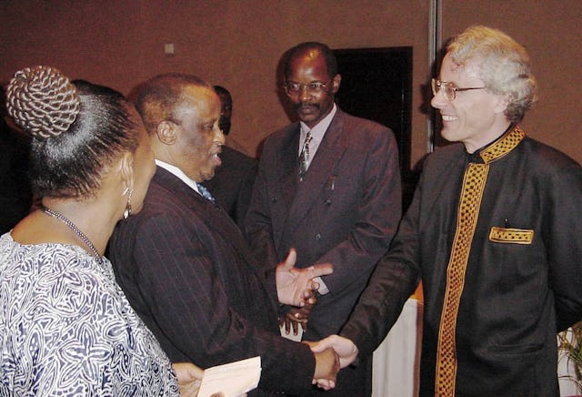Mrs. Lally Warren (left) introducing President Mogae of Botswana to Mr. Gerald Warren (right).| Mr. and Mrs. Warren worked on translations of Baha'i scripture into the native Setswana language. In the background is Enos Makhele, a member of the Continental Board of Counsellors in Africa.