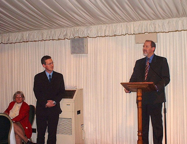 Barney Leith, Secretary-General of the Bahá'í Community of the United Kingdom, addresses the some one hundred participants at the Bahá'í new year's reception in the British House of Commons on 21 March.| MP Lembit Opik, Chair of the All Party Parliamentary Friends of the Bahá'ís, stands to the right.