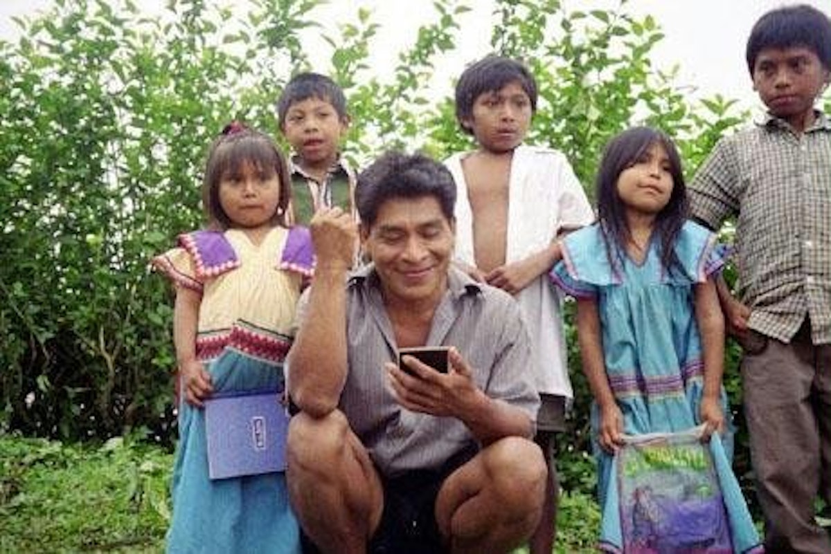 Victorino Rodriguez, with some of his students behind him, examines a Polaroid photograph of his primary school class in the tiny village of Quebrada Venado in the mountains of Western Panama.
