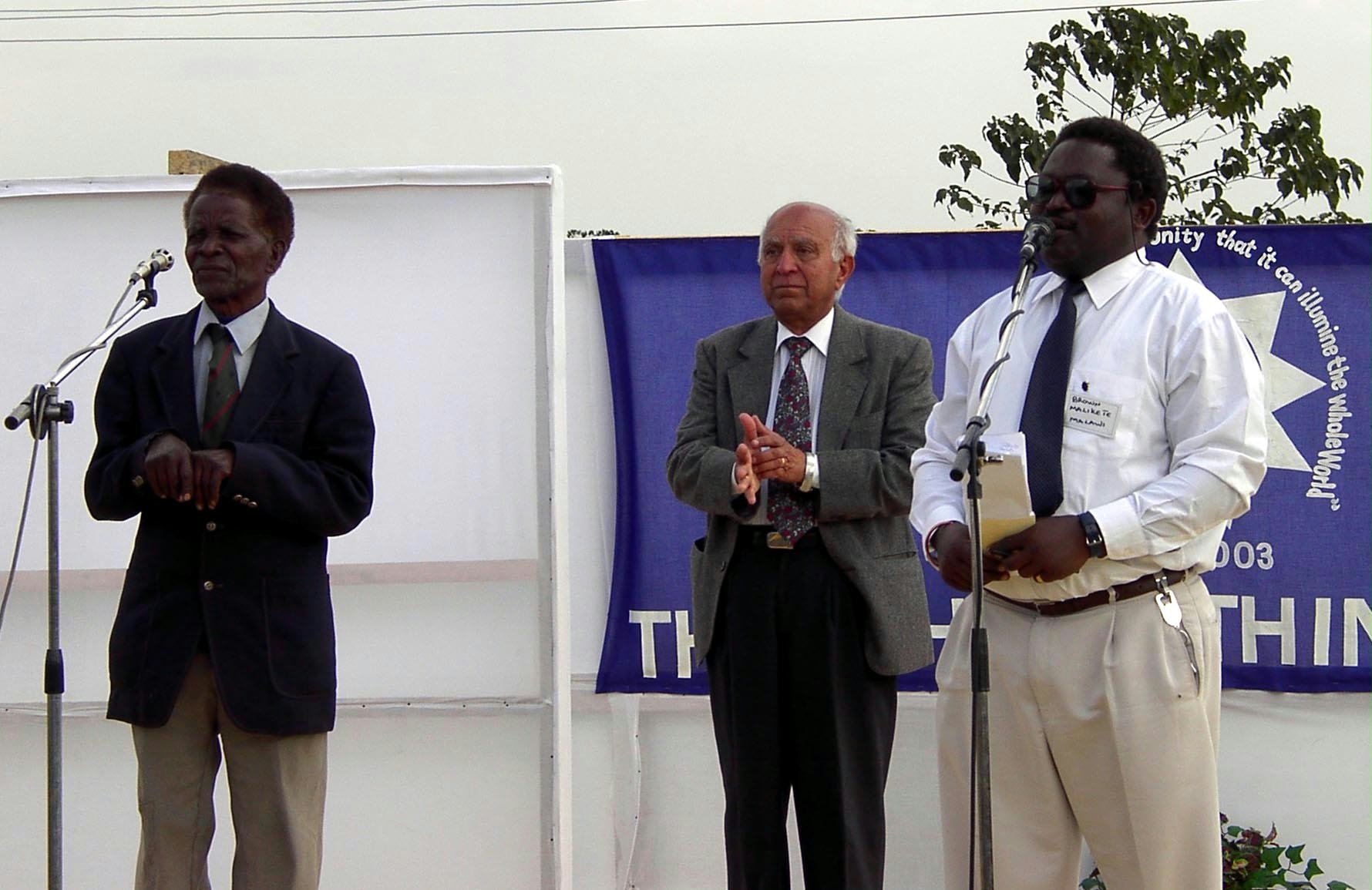 Julius (Robert) Kasakula tells a story while Enayat Sohaili and master of ceremonies, Brown Malikete, look on.