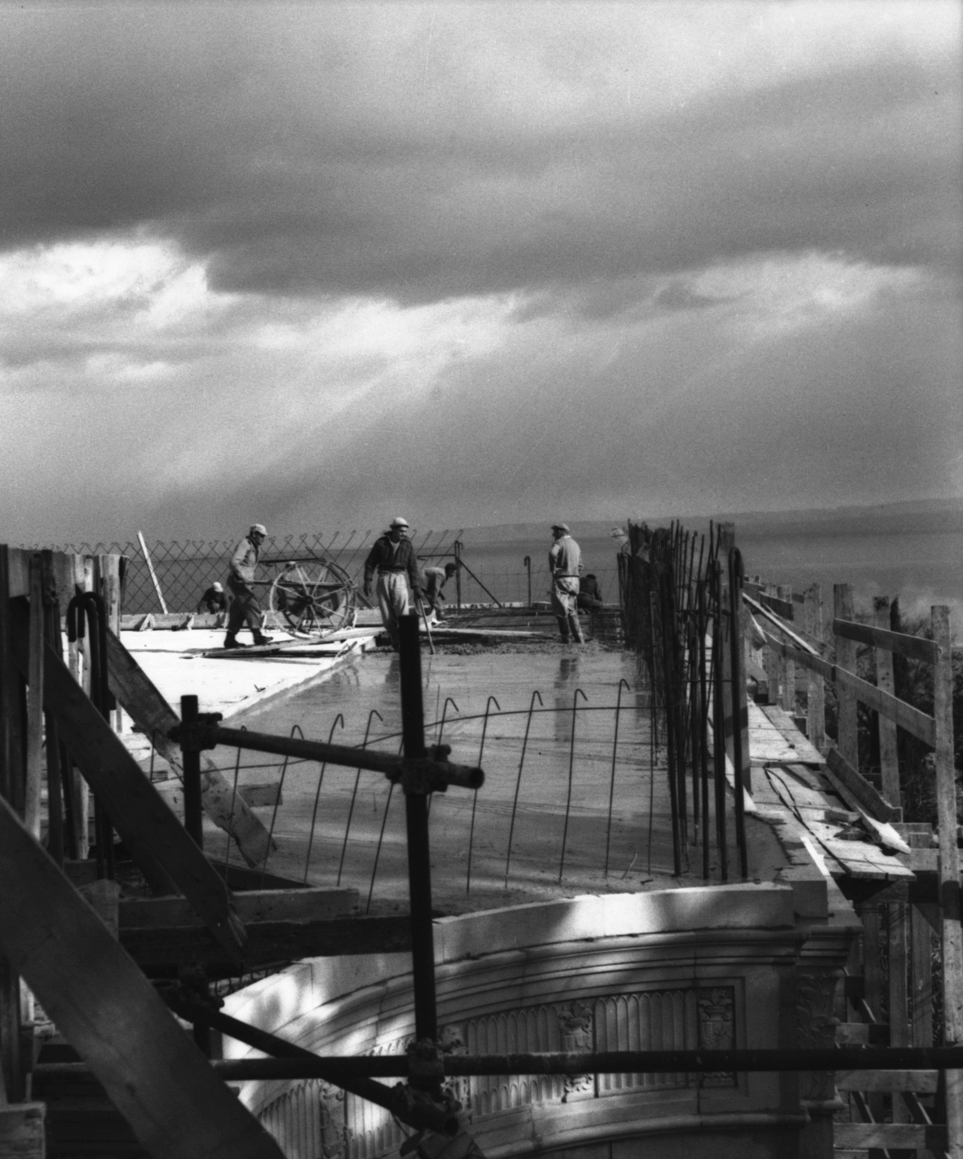 Workmen building the platform above the stone edifice, 1950.