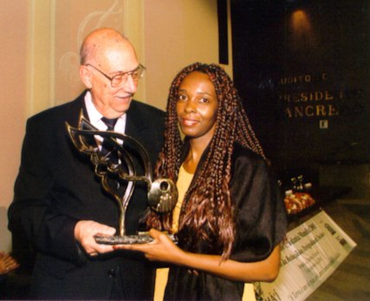 Baha'i representative Osmar Mendes presents an award to Sonia Creide of the Malunga Group of African-descendant Women.