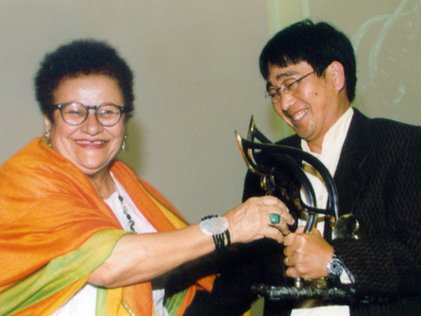 Hildesia Medeiros of the Ministry of Social Security, presents an award to Luiz Takezi Tohara, representing the Gaspar Center for Human Rights.