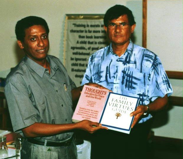 The chairman of the National Spiritual Assembly, Antonio Gopal (right), presents books to Seychelles Minister of Education, Danny Faure.