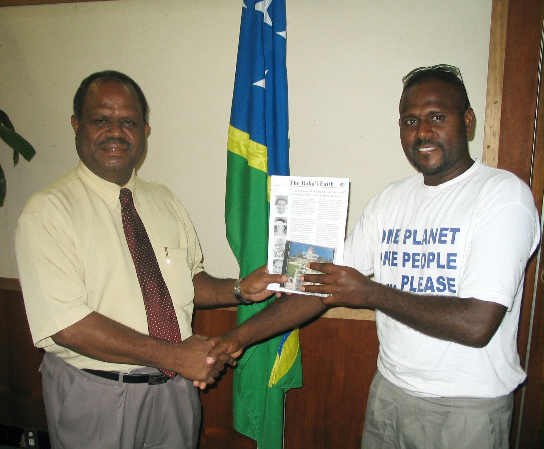 Prime Minister of the Solomon Islands, Sir Allan Kemakeza, (left) receiving a jubilee publication and album from a member of the National Spiritual Assembly, Whitlam Saeni.