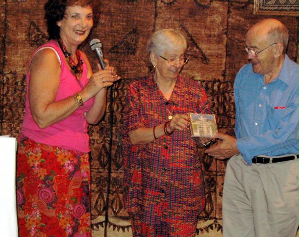 Keithie Saunders (left) presenting an album by the Baha'i youth choir of Honiara to John and Ruhengiz Mills.