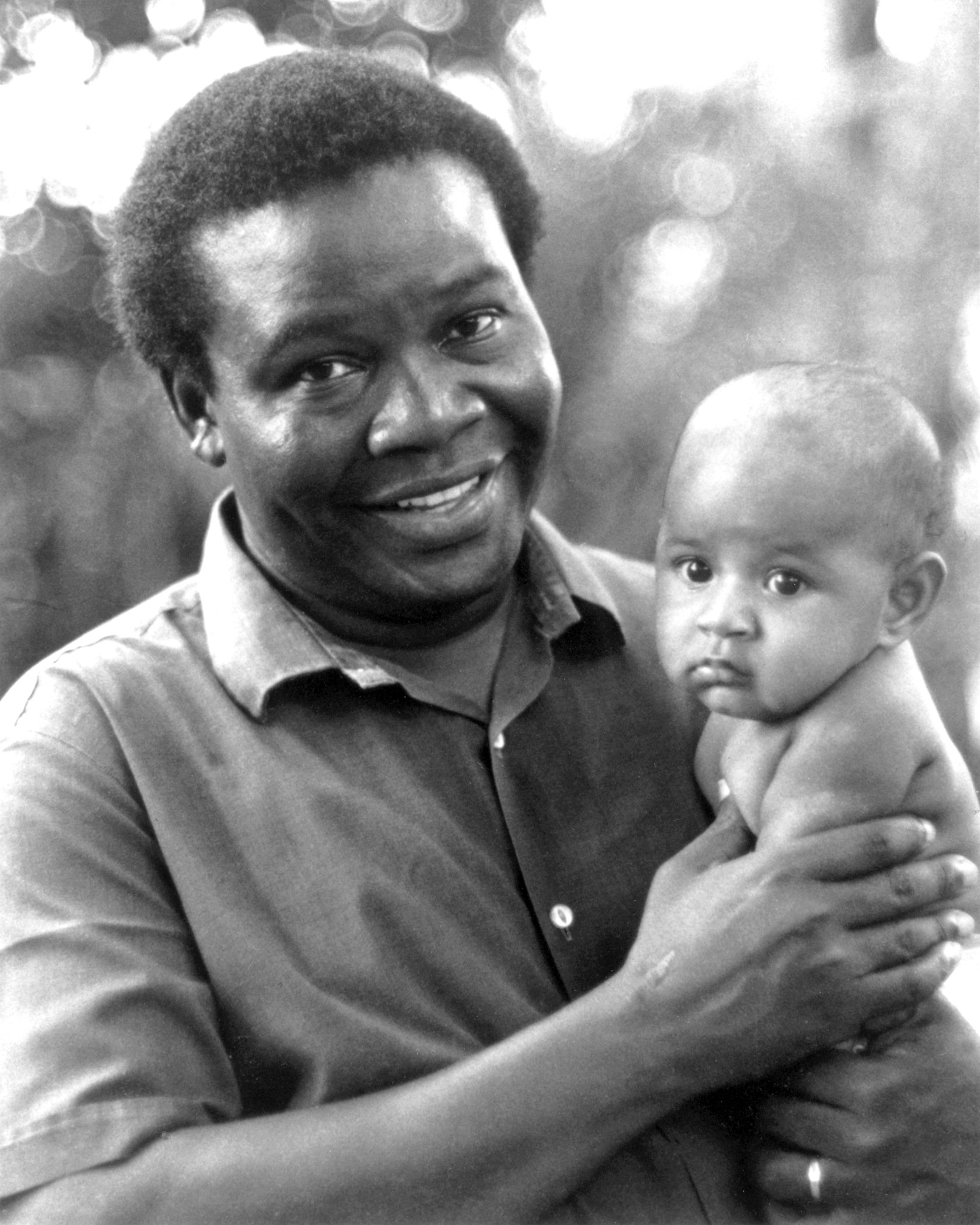 Hand of the Cause of God Enoch Olinga, with a local baby, on a visit to the Solomon Islands.