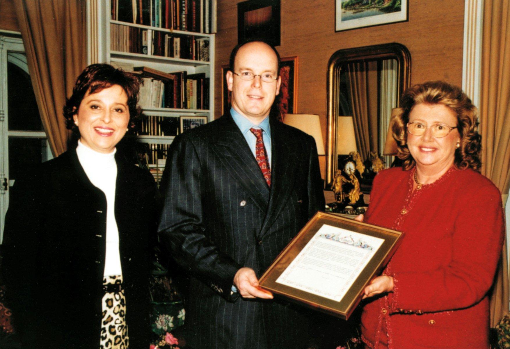 Prince Albert of Monaco receives a Baha'i prayer in Monagasque from (at left) Brenda Abrar of France and Paulette Bodansen of Monaco, 2001.