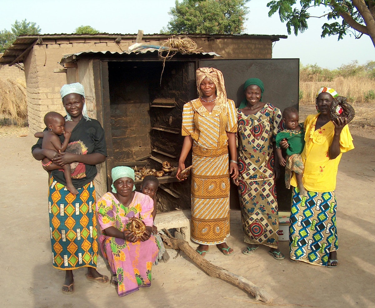 In Gnala, women stand in front of a fish smoker built with the help of APRODEPIT.