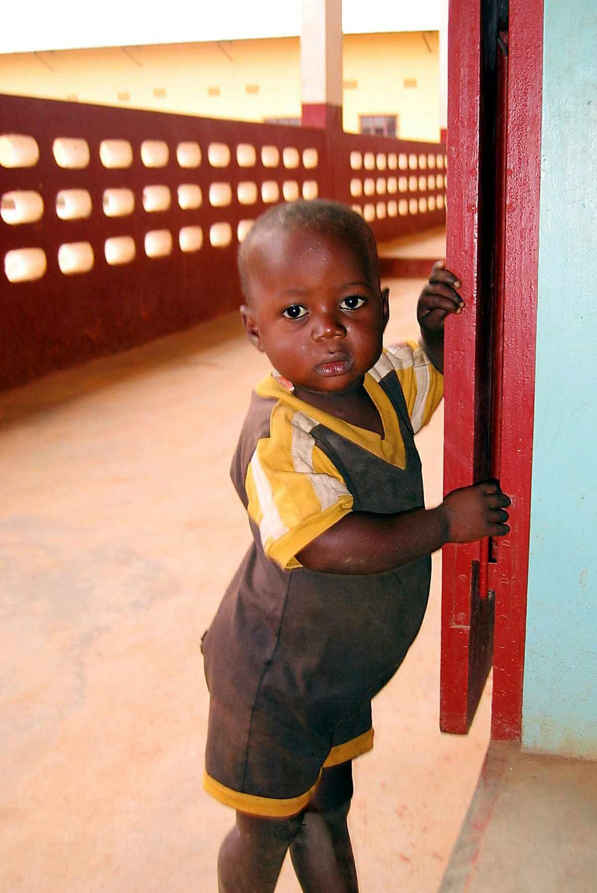 A local boy peeks at the Baha'i youth conference taking place in his neighborhood in N'Zerekore.