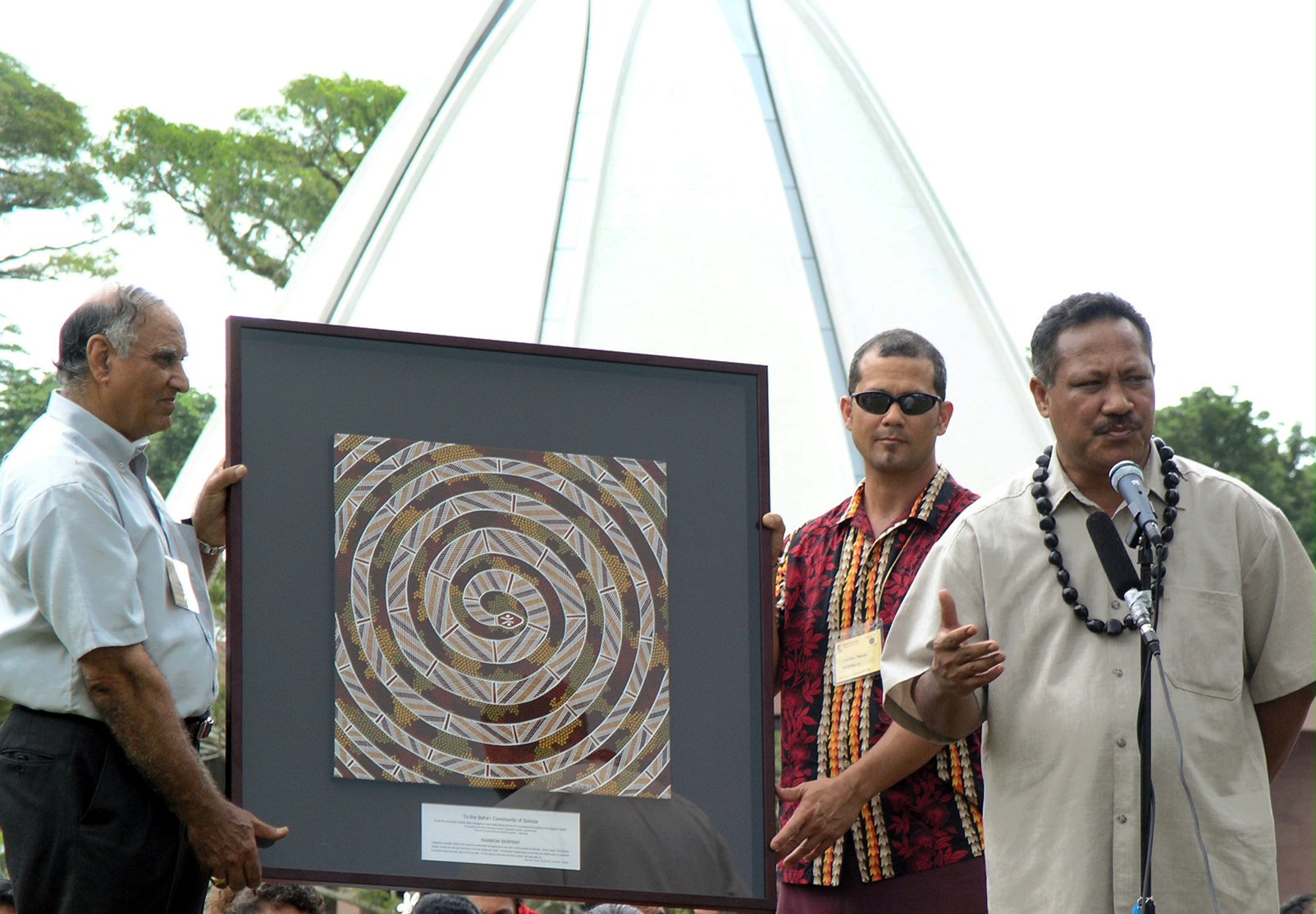 Presentation of a gift from Baha'is in Australia being received at the jubilee by Fereidoun Yazdani (left), a member of the Continental Board of Counsellors, and Titi Nofoagatoto'a (right), the chairman of the National Spiritual Assembly of the Baha'is of Samoa.