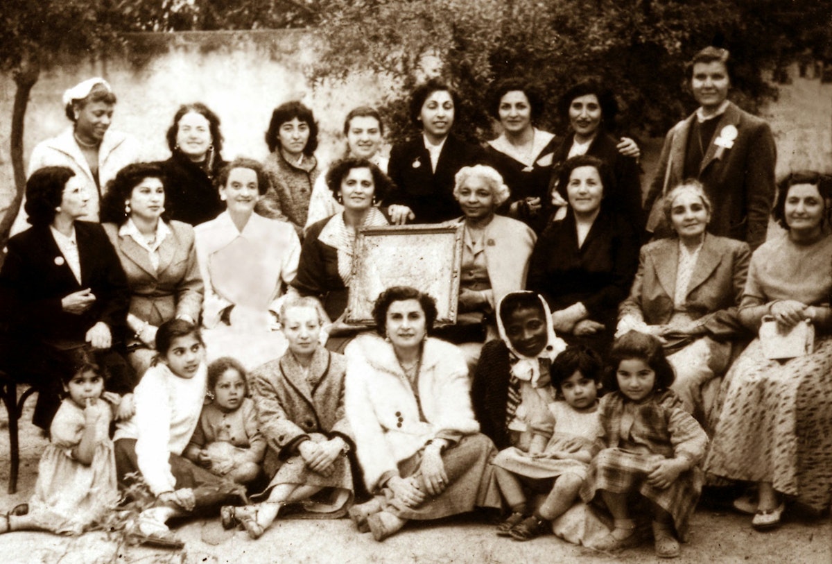 Elsie Austin (wearing coat and holding frame, seated center) with women attending the first Baha'i Convention in Tunis, Tunisia. 1956.
