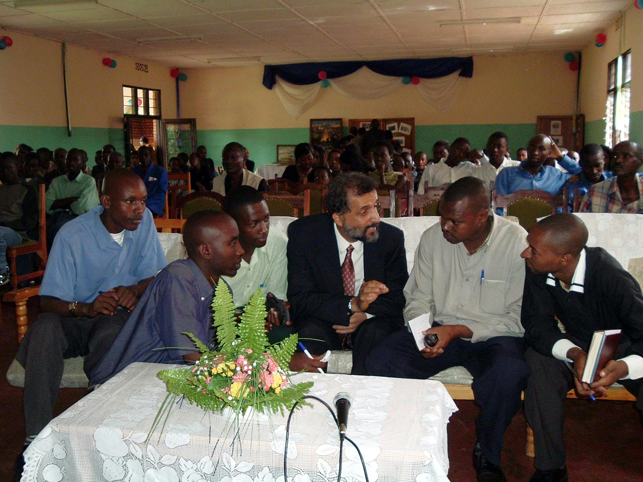 The media took a keen interest in the jubilee festivities of the Baha'i community of Rwanda...Reporters listen to a member of the Continental Board of Counsellors in Africa, Ahmad Parsa (fourth from left.)