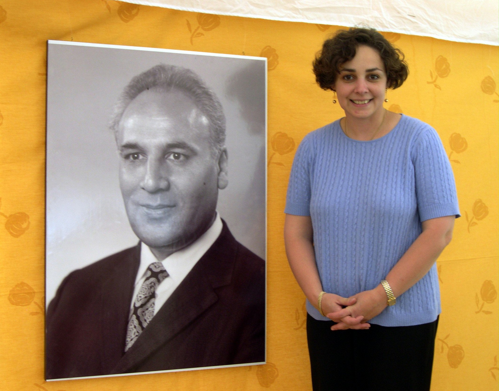 Gisu Muhajir with a photograph of her father, the Hand of the Cause of God Dr. Rahmatu'llah Muhajir, at the "Growth and Victories" conference held in his honor.