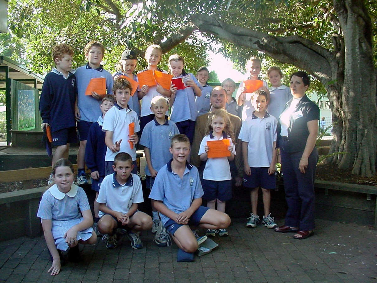 A Baha'i Education in State Schools (BESS) class at the Fig Tree Pocket State School in Brisbane, Queensland, Australia. The deputy principal of the school, Ralf Gruss, is seated at center. The volunteer teacher, Shidan Toloui-Wallace, is at right.