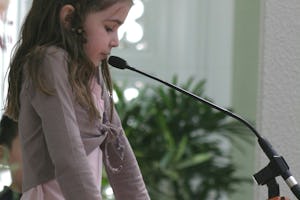 A pupil from a Sydney primary school, Chloe Maclean, reads a prayer at the service held in the House of Worship on Universal Children's Day. Photo by Saba Rouhani.