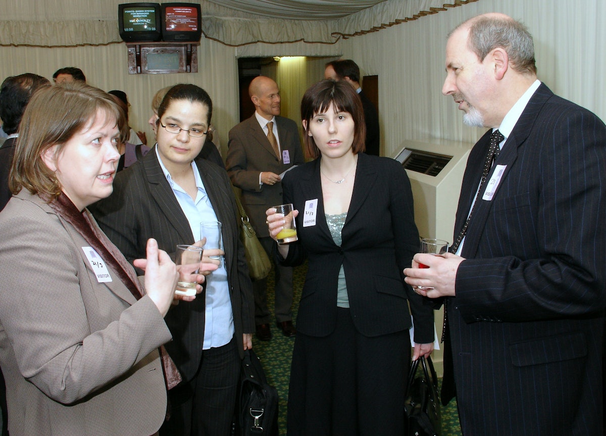 Barney Leith (right), secretary for external affairs of the Baha'i community of the United Kingdom, talks to Dr. Anna Cummins (far left), leader of the Btitish Home Office's Faith Communities Engagement Team, at a Naw-Ruz celebration in the House of Commons on 21 March 2006. Also shown are several other Home Office officials.