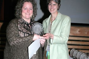 Patricia Tomarelli, shown at left, receiving a "Best of Class" DeRose-Hinkhouse Award for "Sarah Farmer's Dream of Peace" in the "public relations materials" category, for special issue publications. Presenting the award, at right, is Jeanean Merkel, President of the Religion Communicators Council (RCC).