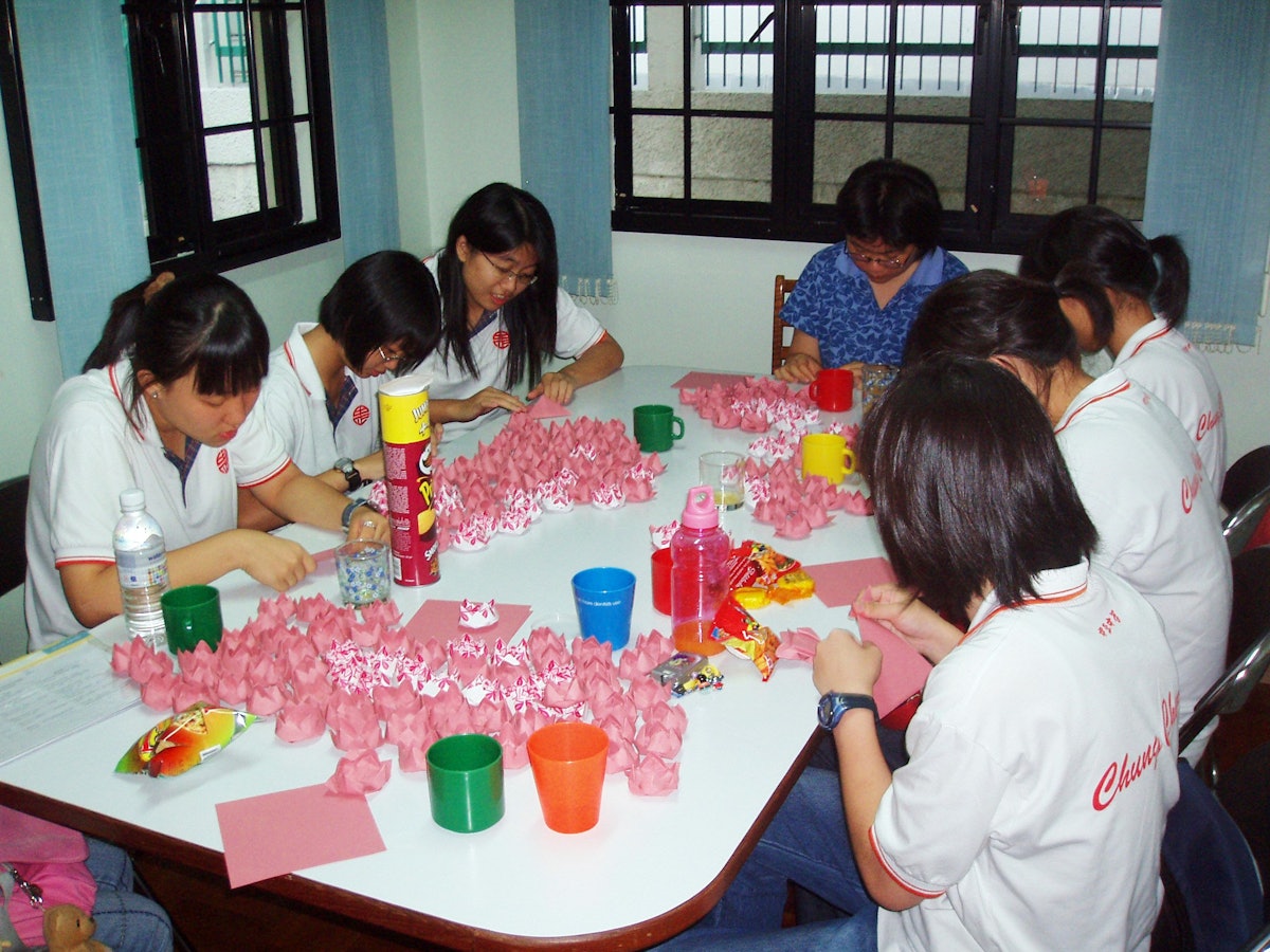 About 40 youth gathered at the Singapore Baha'i Center on 15 April 2006 to fold paper lotuses as part of the Project Million Lotus 2006. Shown here are six secondary school students from Chung Cheng High School with Baha'i Sabrina Han (center) in the blue shirt.