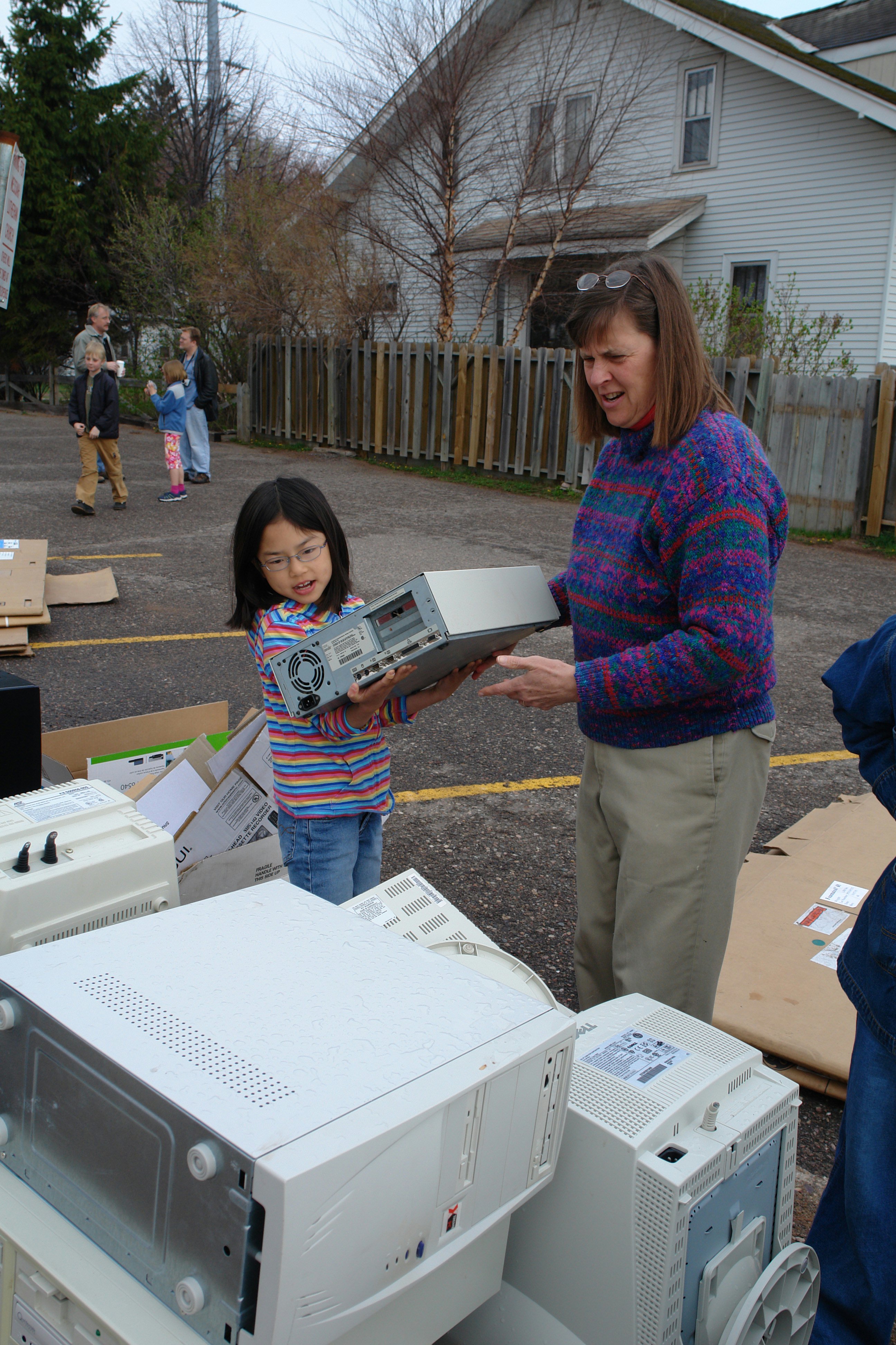 Eve McCowen, 9, tosses an old computer into a recycling pile under the watchful eye of her mother, Lisa, on 22 April 2006 during the Earth Keeper Clean Sweep in Marquette, Michigan, USA. Eve and Lisa McCowen were among nine Baha'is who joined some 350 other volunteers to help collect electronic waste on Michigan's Upper Penninsula in an interfaith effort. (Photo by Greg Peterson.)