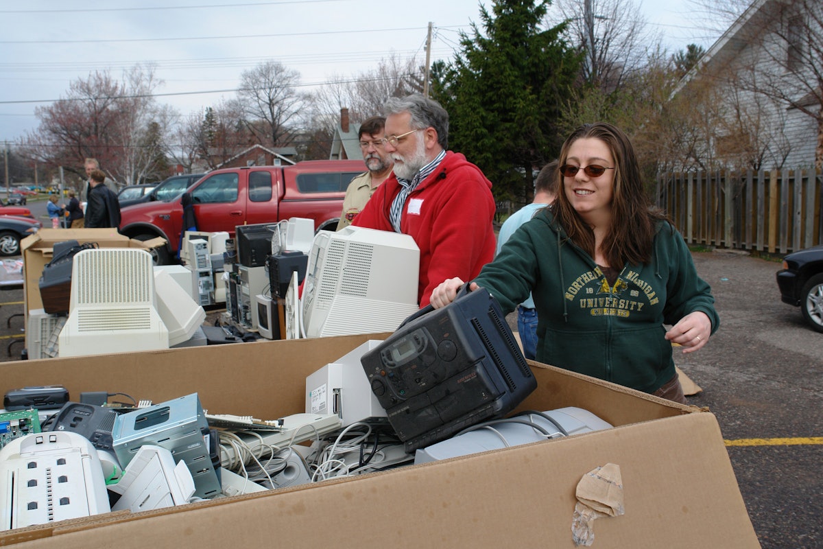 Rehema Clarken, right, puts an old CD player into an "e-waste" recycling bin during the Earth Keepers Clean Sweep in Marquette, Michigan, on 22 April 2006. In the red jacket is Dennis McCowen. Both are Baha'is. (Photo by Greg Peterson.)