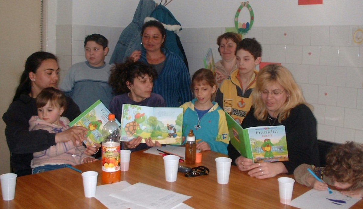 A group of mothers read "Franklin Knows" to their children in a weekly meeting in Jasz Arokszalas.