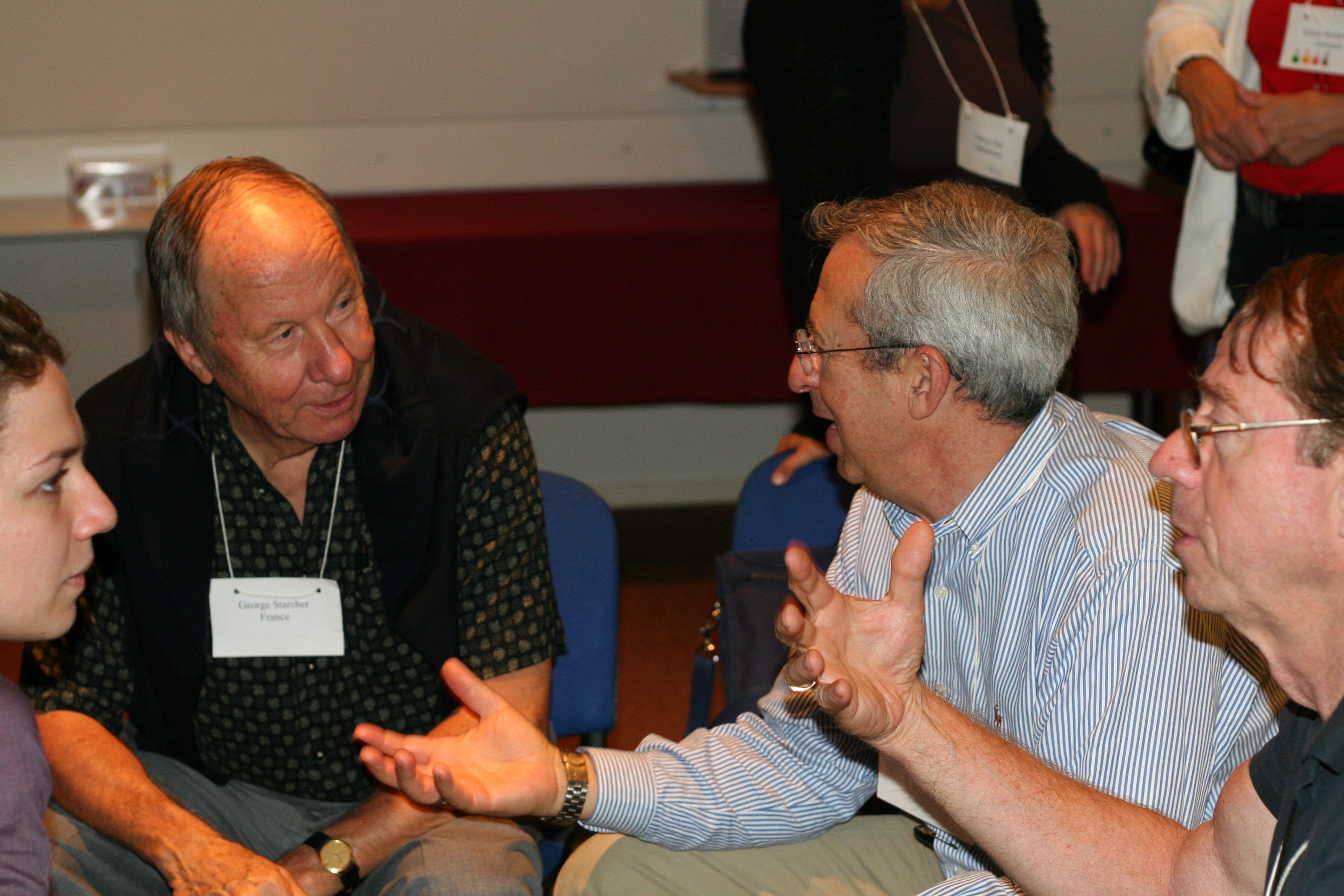 George Starcher (back left), EBBF co-founder, and Larry Miller (back right) actively engaged in conversation with each other, while Arthur Dahl (front right), an EBBF governing board member, explains a concept to Cornelia Raportaru of AIESEC International.