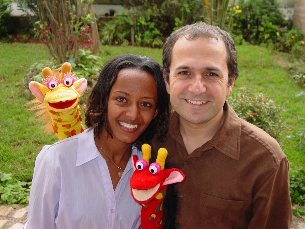 Bruktawit and Shane Etzenhouser pose with puppets Tsehai, the yellow giraffe, and Tsehai's younger brother, Fikir.