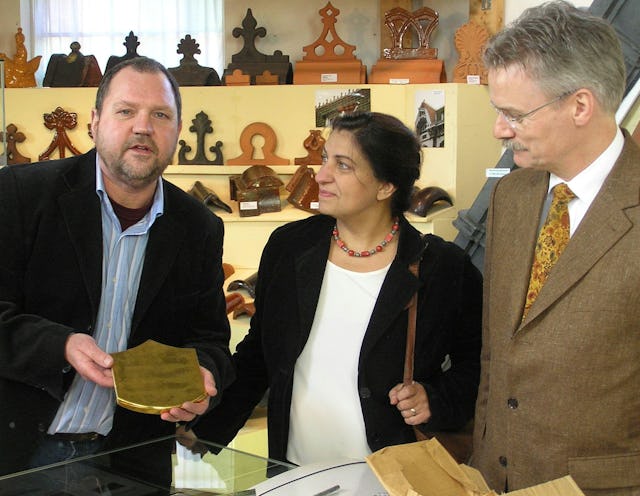 Huub Mombers, left, receives a gilded tile from the Shrine of the Bab for his museum in Alem, in Holland. Offering the tile on permanent loan, on behalf of the Baha'is of the Netherlands, are Elaheh Verhey-Shahgholi, center, and Jelle de Vries. The ceremony was on 3 February 2007.