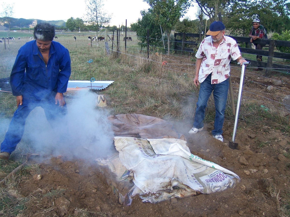 Melini Taufalele and Geoff Jervis uncover the umu, the underground oven used for their Naw Ruz dinner in Eureka, a small rural settlement in New Zealand.