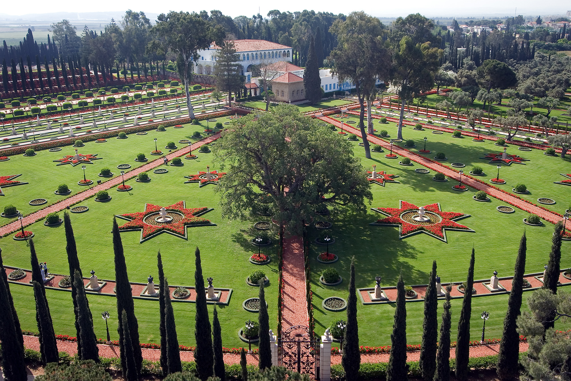 This view shows the site of yesterday's Holy Day commemoration. The Baha'is were seated in chairs at the outer periphery of the circle shown here, facing the Shrine of Baha'u'llah, which is the square, brick structure at the forefront of the buildings. The Mansion of Bahji, where Baha'u'llah lived His final years, is the large white building.