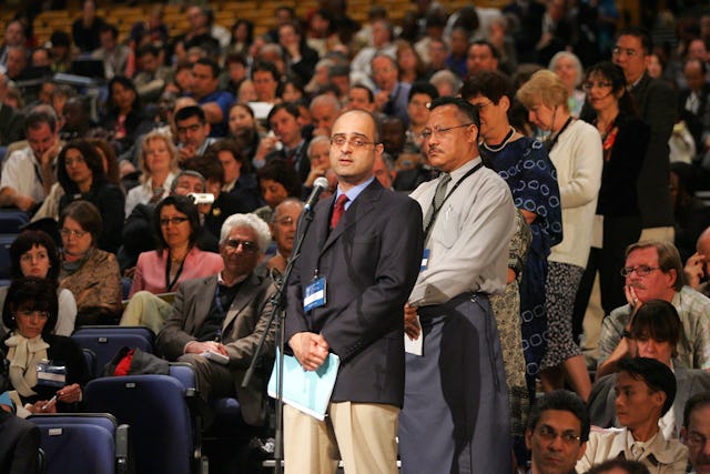 Delegates line up to share information about Baha’i core activities on different continents.