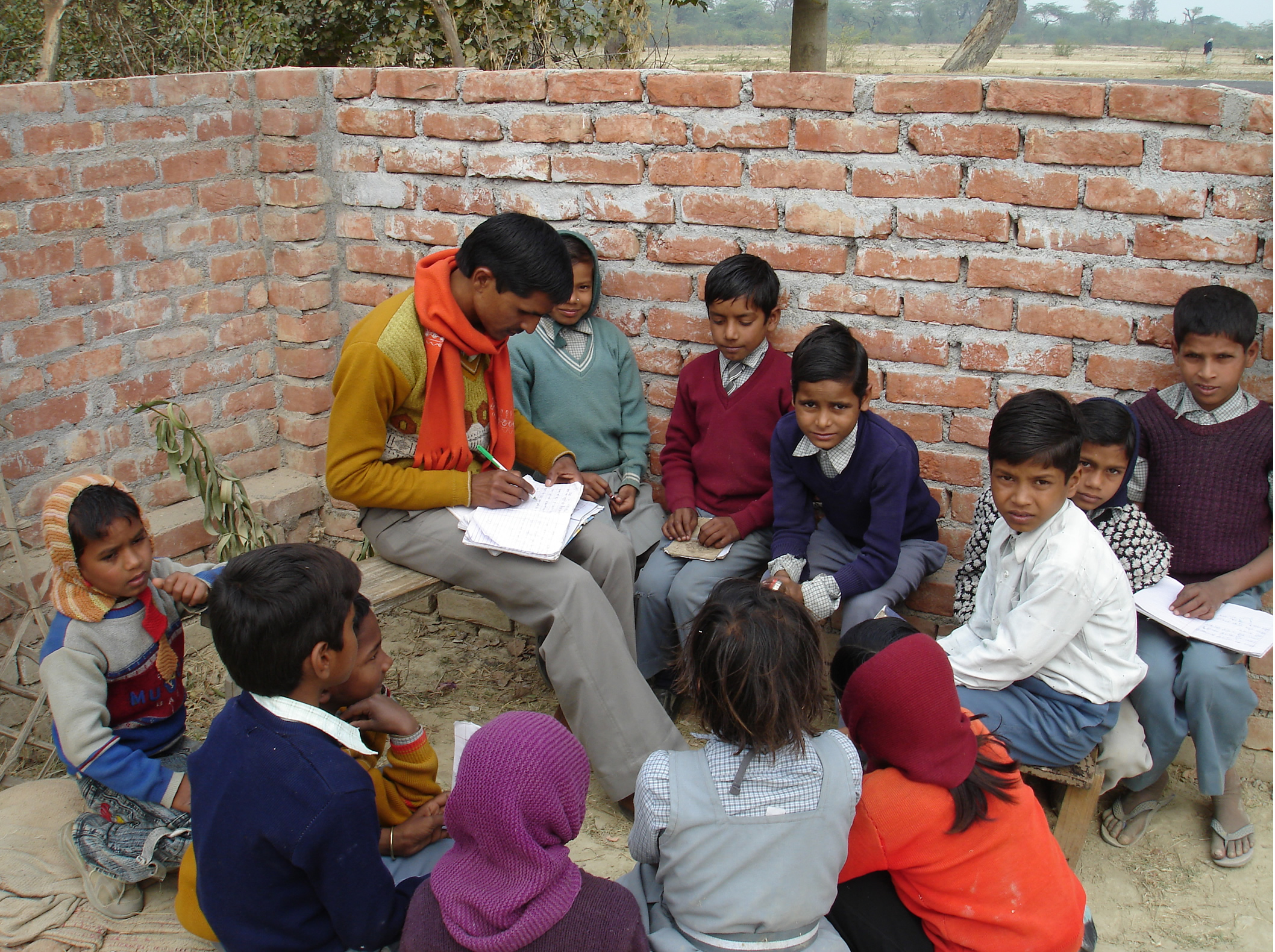 Children gather around a teacher at Vinod Kumar Yadav’s Glory Public School.