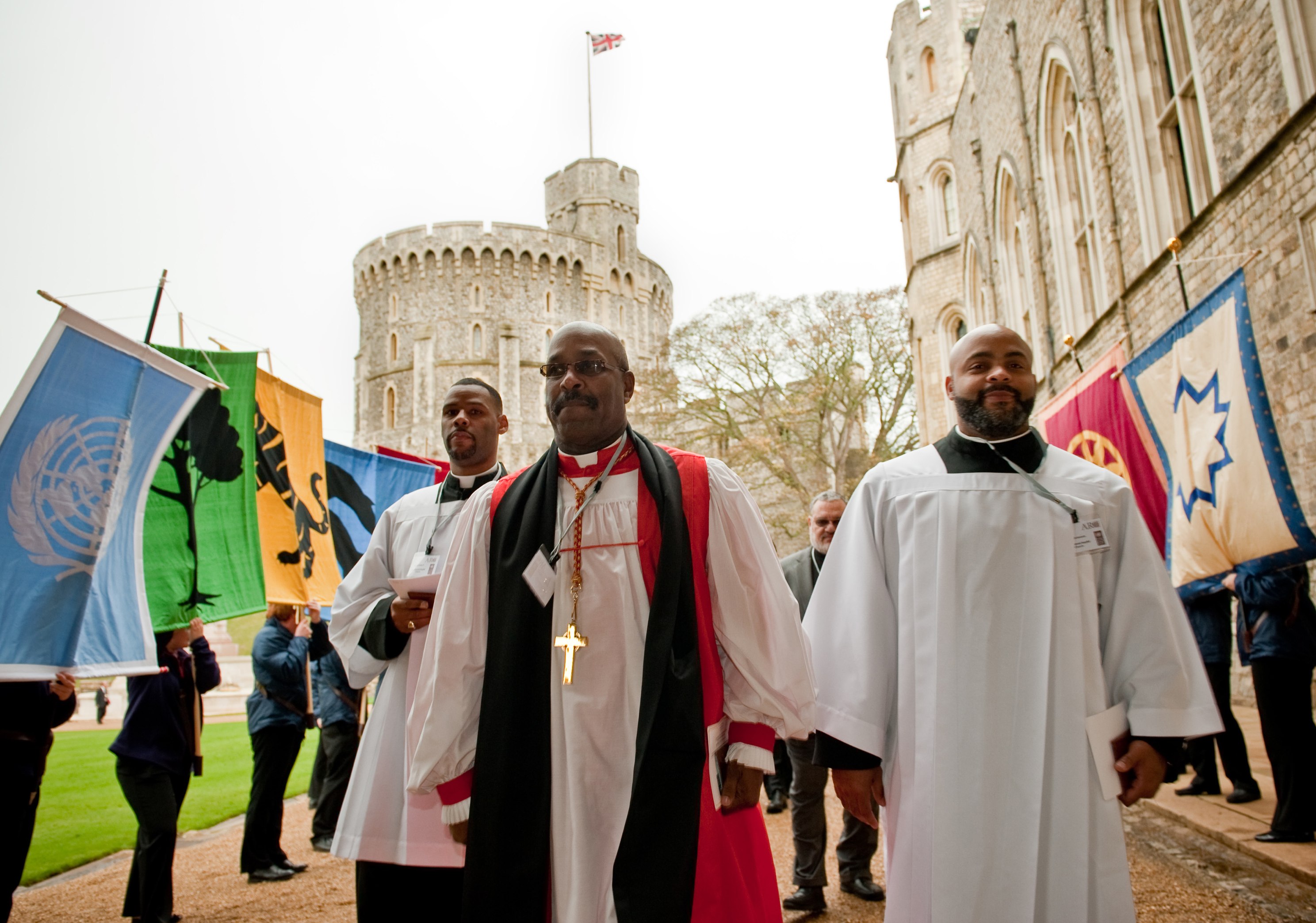 The procession passes by the UN flag at left and a number of religious symbols, including a Baha'i symbol at right.