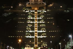 The Shrine of the Bab on Mount Carmel in Haifa is illuminated at night, but the familiar golden dome is covered by a shroud while restoration work is under way. (Baha’i World Centre photo. All rights reserved.)