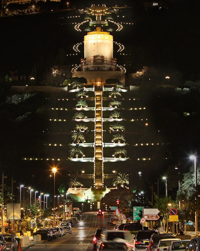 The Shrine of the Bab on Mount Carmel in Haifa is illuminated at night, but the familiar golden dome is covered by a shroud while restoration work is under way. (Baha’i World Centre photo. All rights reserved.)
