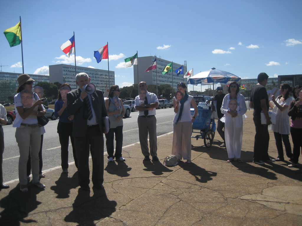 Brazilian Congressman Luiz Couto addresses human rights campaigners in Brasilia, carrying masks depicting the seven imprisoned Iranian Baha'i leaders.